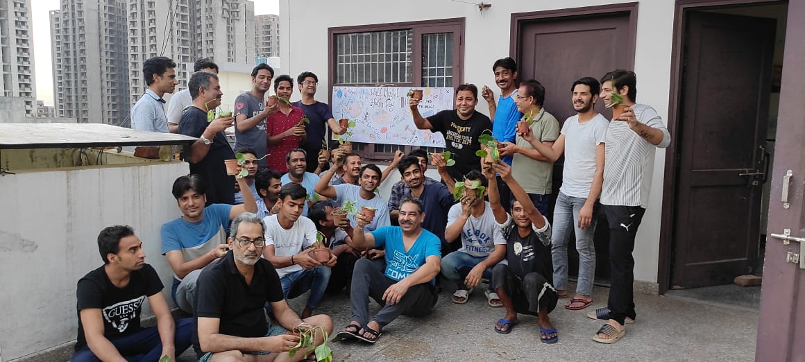 Group photograph of SimranShri patients holding planted saplings on the terrace